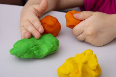 Colorful clay in kids hands, preschooler has motor skills