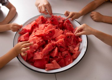 Çocuklar ellerinde kesilmiş karpuz, yukarısı manzaralı.