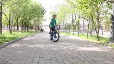 Çocuk parkta bisiklet sürüyor.