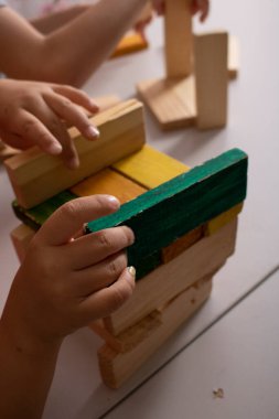 Two kids hands playing with colorful wooden building blocks