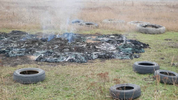 旧轮胎躺在焚烧橡胶的火堆周围 图库图片
