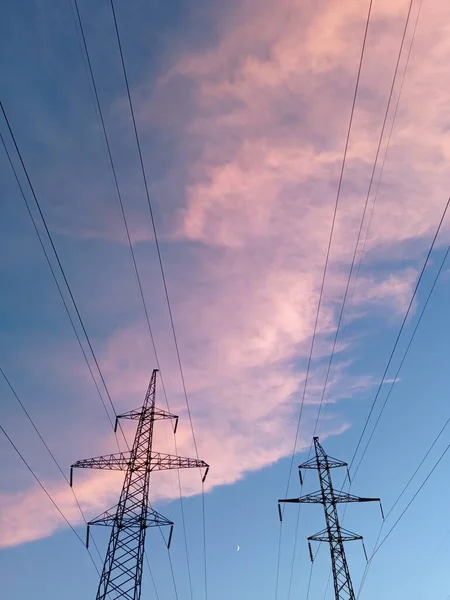Electricity distribution station.Silhouette high voltage electric towers at sunset time. High-voltage power lines.Moon