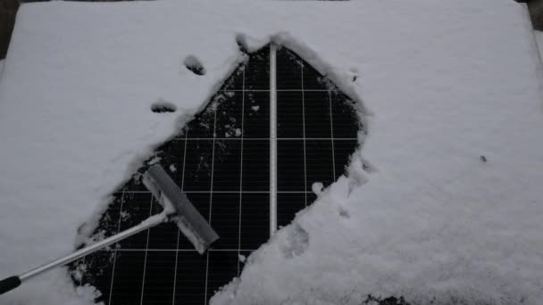 Schnee von der Solarzelle entfernen. Das Sonnenelement unter dem Schnee. Sonnensymbol. Sauberere Solarzellen erzeugen mehr Energie.