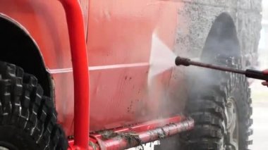 Topraktan, tozdan ve enkazdan yüksek basınçlı çamaşır makinesiyle bir off-road aracını yıkamak.