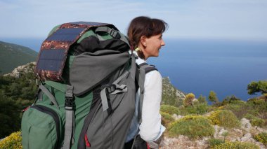  Sırt çantasındaki güneş panelleriyle deniz kıyısındaki kız turist.