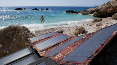  Güneş panelleri taşa sabitlendi. Kız turistler denizde yıkanır..