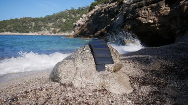 Bir güneş paneli deniz kıyısında bir enerji bankasına saldırıyor.