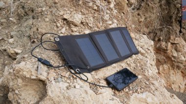 Bir güneş paneli, bir akıllı telefonu toprak yamaçta şarj eder