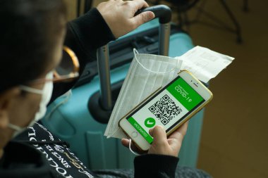 Aşılanmış kadın covid-19 salgını sırasında seyahat için cep telefonunda dijital sağlık pasaport uygulaması kullanıyor..