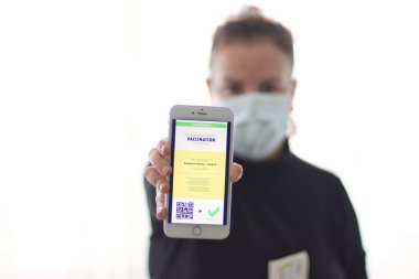 Aşı sertifikası ve seyahat için AB Dijital Yeşil Geçiş Kartı göstermek için akıllı telefondaki mobil uygulamayı kullanan genç bir kadın. Dokunulmazlık pasaport, sağlık ve aşı kavramı