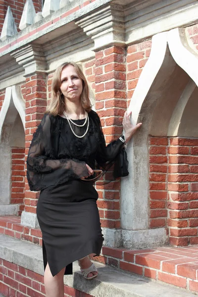 Une femme se tient près du mur de briques — Photo