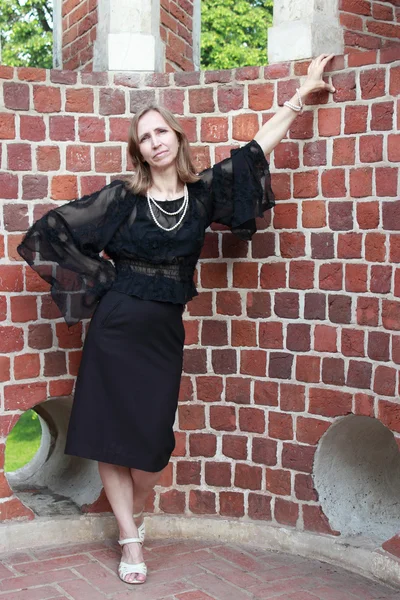 Uma mulher está perto da parede de tijolos — Fotografia de Stock