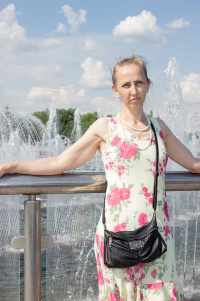 Kobieta stojąc przy fontannie — Zdjęcie stockowe