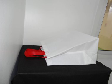 Beautiful Non Woven grocery shopping white bag with red handle loop isolated on black table against white wall background