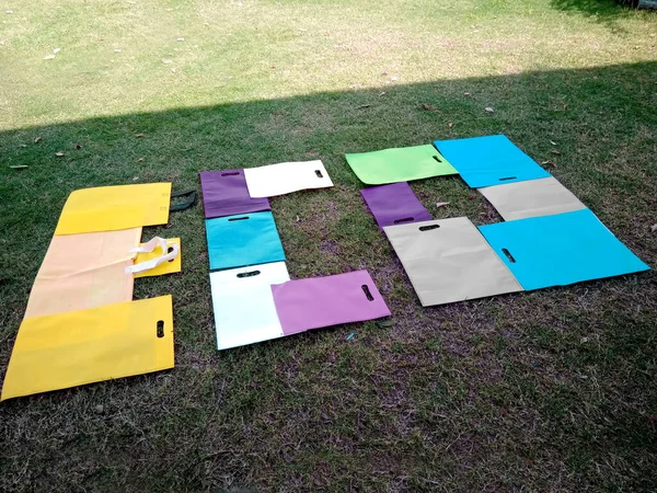 ECO Word Showing with Non Woven D-Cut Colorful Bags isolated on green field. Environment Friendly Concept