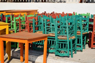 Sandalye yığını, kapalı restoran Covid-19 Salgın Kapanması. Tahta bar koltukları dışarı istiflenmiş. Girit Adası, Yunanistan