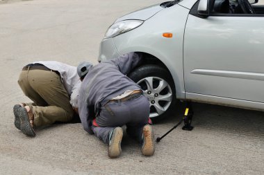 Ouarzazate, Fas - 02 Ağustos: Yoldaki arabanın bozulması. Ouarzazate, Fas 'ta 2 Ağustos 2015' te araba motoru tamiri için araba altına bakan insanlar