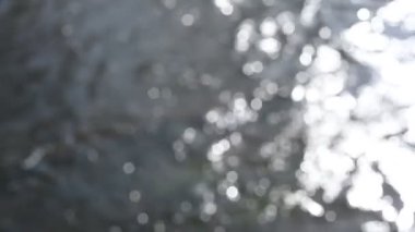 Bokeh güneşi su yüzeyine yansıyor. Güneş ışınları su akıntısında titreşiyor.. 