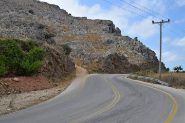 Dağlarda otoyol, her iki tarafta kayalar ve arka planda dağlar. Girit Adası, Yunanistan