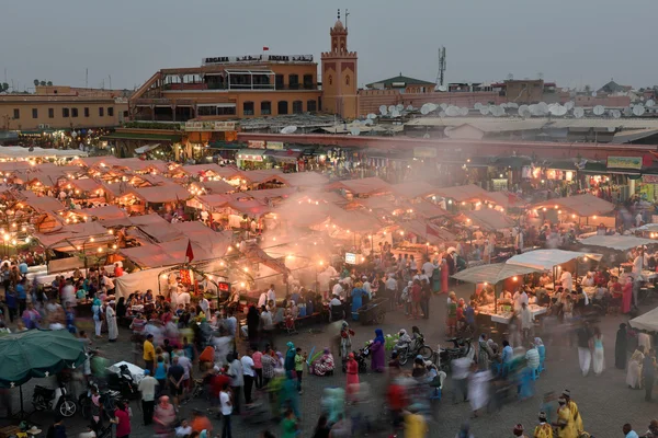 Menschen besuchen den jemaa el fna Platz bei Sonnenuntergang — Stockfoto