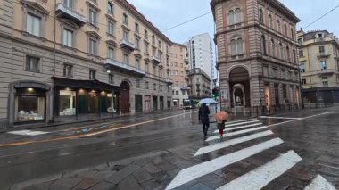 Torino, İtalya - 25 Aralık 2025: Eski Torino kentinde yağmurda yürüyen tanımlanamayan kişiler.