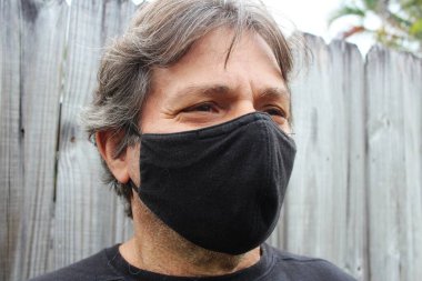 60 yaşındaki bir adam salgın sırasında siyah bir maske takıyor.