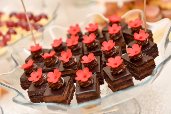 Bolos de chocolate com flor vermelha colocados em um prato de vidro — Fotografia de Stock