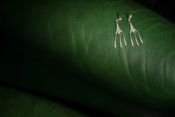 Oorbellen zittend op een groen leder texture — Stockfoto