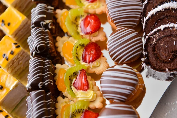 Diferentes tipos de pasteles en una placa y con luz lateral — Foto de Stock