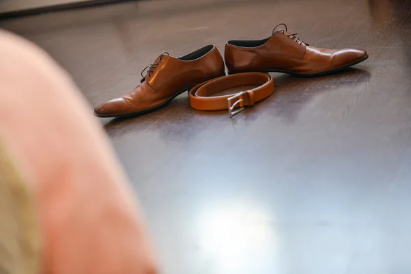 Sapatos de couro marrom e cinto sentado em um chão de madeira — Fotografia de Stock