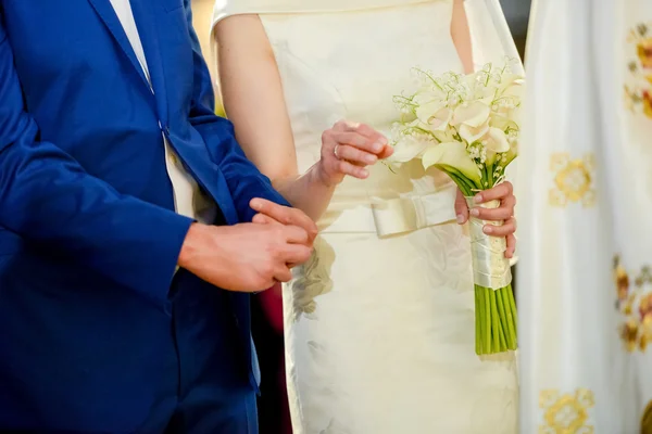 Wedding bouquet holding by bride next to her groom in a church — Stock Photo, Image