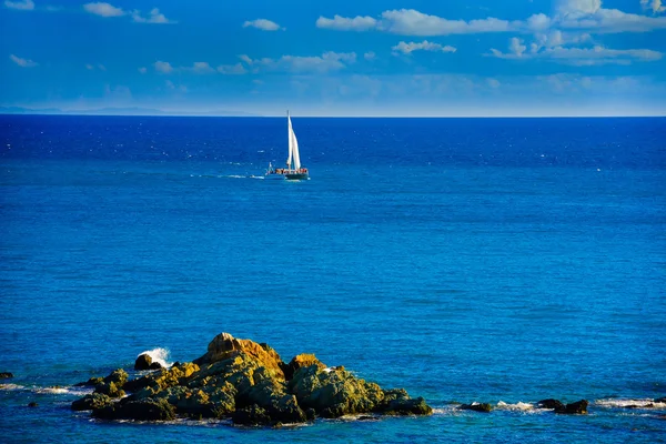 Sailing boat on ocean with big rock on foreground — Stock Photo, Image