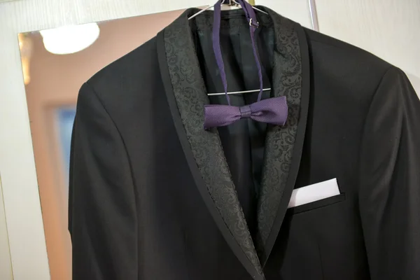Black suit with purple bowtie hanging closet — Stock Photo, Image