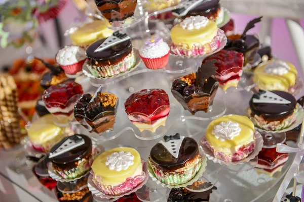 Viele bunte Cupcakes auf einem Plastikständer mit seitlichem Licht — Stockfoto