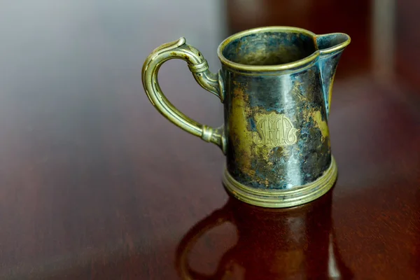 Old brass cup sitting on a glossy wood — Stock Photo, Image