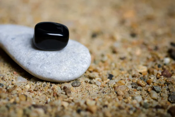 Серые и черные камни на песчаном фоне — стоковое фото