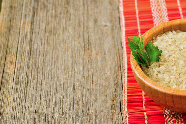 Isolated bowl with brown uncooked rice and leaf of parsley