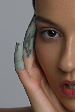 Islak, parlak tenli ve büyük gri gözlü bir kadının yarım yüzünün güzelliği. Modaya uygun doğal makyaj ve ıslak yüz kılları. Öpülmüş dudaklı pembe ruj.