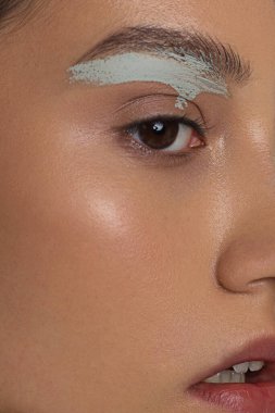 Islak, parlak tenli ve büyük gri gözlü bir kadının yarım yüzünün güzelliği. Modaya uygun doğal makyaj ve ıslak yüz kılları. Öpülmüş dudaklı pembe ruj.