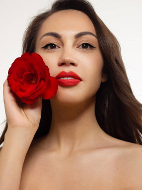 Parlak makyajlı, seksi kırmızı çizgili güzel bir kadın. Kadınların göz kapaklarında moda oku şekli. Doğal dudaklar. Şık bir akşam makyajı. Lüks uzun dalga saçı. Çiçeklerle parlayan cilt