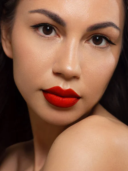 The beautiful brunette with evening cosmetics. Clean and smooth skin of the woman. Fashionable cosmetics.Bright shadows and lipstick. Cosmetology. Red chubby lips. Long eyelashes. Permanent make-up