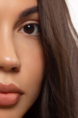 Güzel derisi, çıplak makyajı, göz kalemi, uzun kirpikleri, kabarık doğal dudakları ve beyaz çiçekleri olan bir yüz portresi. Moda fotoğrafçılığı. Kozmetik ve kaplıca. Baharın tazeliği