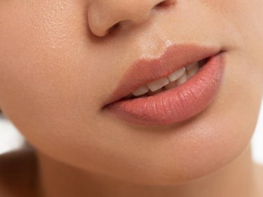 Moda doğal bej ruj makyajlı bir kadının dudaklarının yakın çekimi. Makro seksi soluk ruj makyajı. Yumuşak, saf ten. Kozmetoloji, Spa, dudaklarda artış