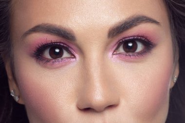 Modaya uygun pembe dumanlı gölgeleri ve son derece uzun kirpikleri olan güzel kahverengi gözlü makro. Kozmetik, kaş düzeltme, kirpik uzatma, makyaj, kozmetik, görme, kontak lens.