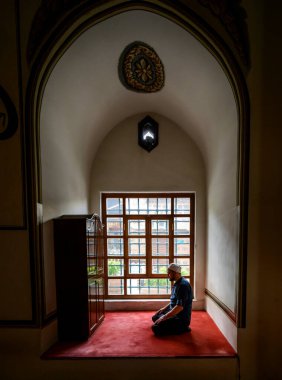 BURSA, TURKEY - 4 Temmuz 04: Büyük cami, Türkiye 'nin Bursa kentinde 4 Temmuz 2020' de pencerenin önündeki Müslüman namazı. 1396-1400 yılları arasında inşa edilen dini bina, Osmanlı İmparatorluğu 'nun ilk orijinal mimari yapılarından biridir..