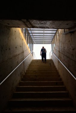 Adam karanlık ortamda merdivenden ışığa doğru yürüyor..