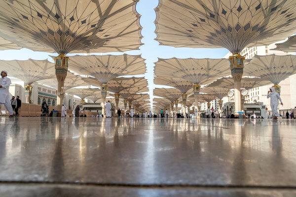 Паломники ходят под гигантскими зонтиками в мечети Набави
