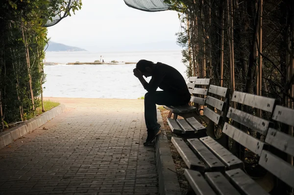 Jovem sentado parecendo chateado Imagem De Stock