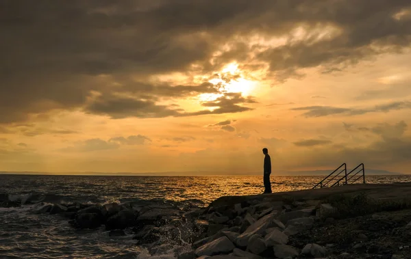 Silhouette of young standing on beach at sunset — Stock Photo, Image