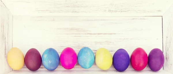 Colorful Easter eggs in basket on wooden background — Stock Photo, Image